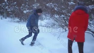 一对年轻夫妇在冬季公园散步，一个男人和一个女孩在公园的雪地里玩耍。